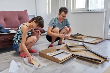 Yeni evlerinde mobilya montajı yapan genç bir çift.