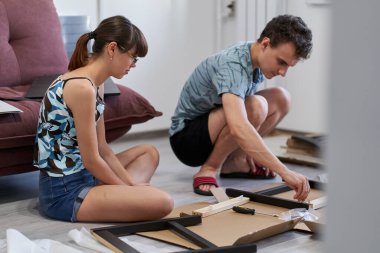 Yeni evlerinde mobilya montajı yapan genç bir çift.