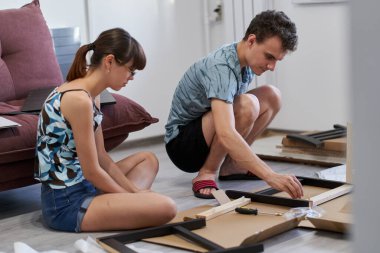 Yeni evlerinde mobilya montajı yapan genç bir çift.