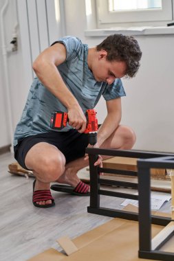 Genç adam yeni evinde mobilya montajı yapıyor, yeni hayat konsepti.