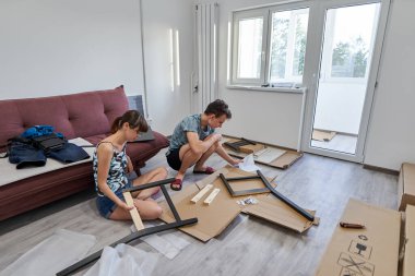 Yeni evlerinde mobilya montajı yapan genç bir çift.