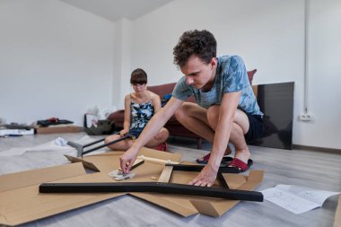 Yeni evlerinde mobilya montajı yapan genç bir çift.