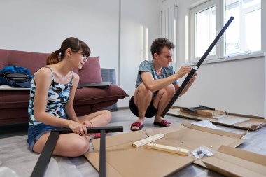 Yeni evlerinde mobilya montajı yapan genç bir çift.