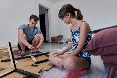 Yeni evlerinde mobilya montajı yapan genç bir çift.