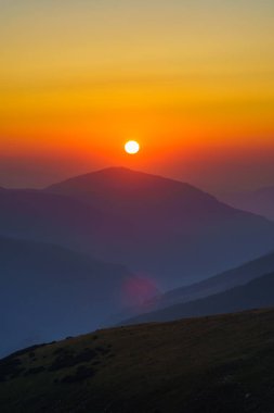 Yaz mevsiminde, dağlarda gün doğumuyla birlikte canlı bir manzara.