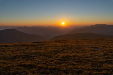Yaz mevsiminde, dağlarda gün doğumuyla birlikte canlı bir manzara.