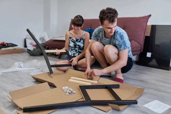 Young couple assembling furniture in their new home, new life concept