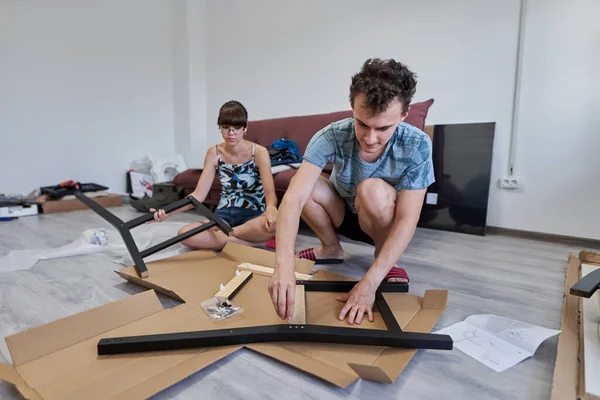 Yeni evlerinde mobilya montajı yapan genç bir çift.