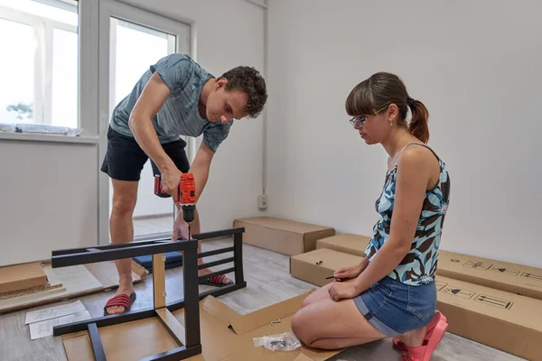 Yeni evlerinde mobilya montajı yapan genç bir çift.