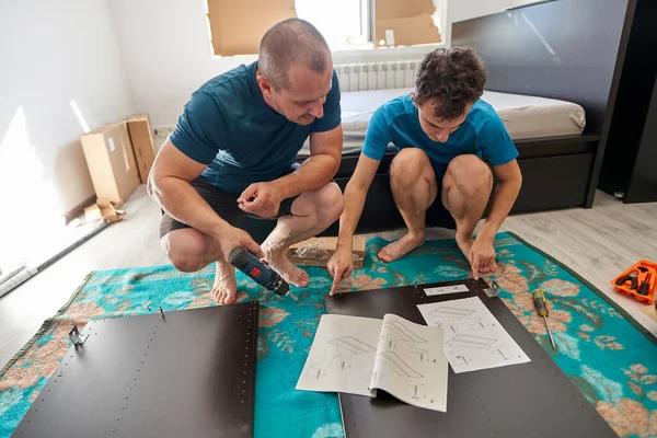 Père Aidant Son Fils Assembler Construire Les Meubles Dans Nouvelle Images De Stock Libres De Droits