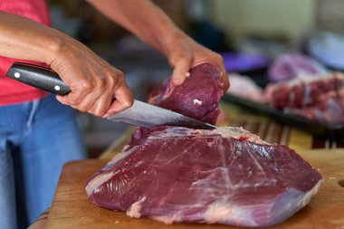 Kadının elleri et kesiyor, evde et hazırlıyor.