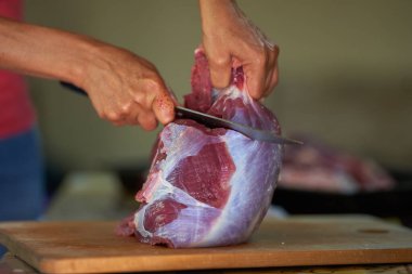 Kadının elleri et kesiyor, evde et hazırlıyor.