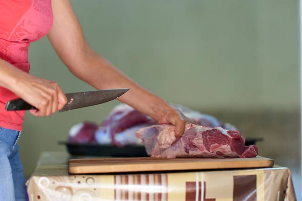 女人的手在切牛肉 在家里准备肉 免版税图库图片