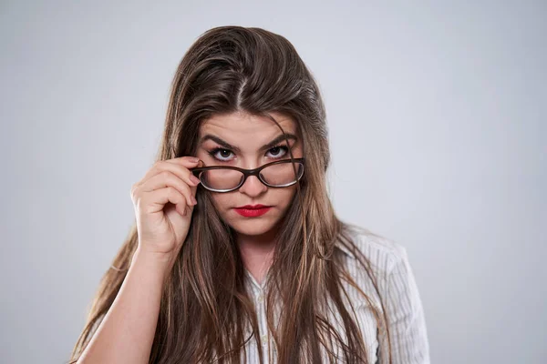 一个戴着灰色背景眼镜的可疑年轻女商人的身份 — 图库照片