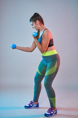 Ayrıca spor yapan kendine güvenen güzel bir kadın. Mavi-kırmızı tonlama. Stüdyo çekimi.