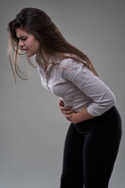 Şiddetli karın ağrısı olan bir iş kadını. Stüdyo resmi gri üzerine.