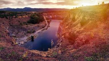 Eski bir taş ocağında oluşmuş bir göl manzarası tortulu kayalar ve görülebilir jeolojik katmanlar.