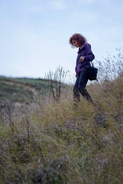 Akşam yürüyüşünde gün batımında kameralı bir turist kadın.