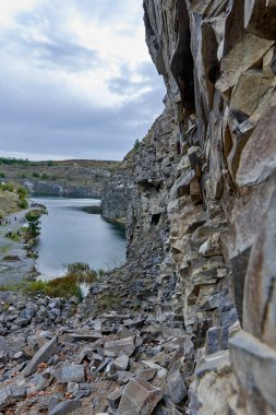 Eski bir taş ocağında oluşmuş bir göl manzarası tortulu kayalar ve görülebilir jeolojik katmanlar.