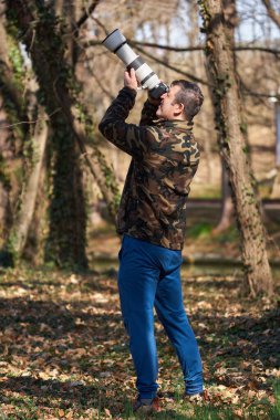 Ormanda vahşi yaşam ve doğa fotoğrafçısı, kamera ve uzun tele objektifle.