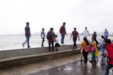 MUMBAI, INDIA - JULY 2, 2018: Unidentified people visit promenade in South Mumbai. The promenade is an open space where people could meet friends and just spend time. clipart