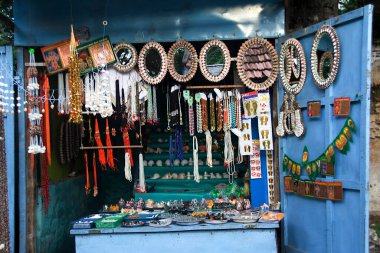 Aynalar, kolyeler, çıkartmalar, deniz kabukları gibi çeşitli nesnelerin görüntüsü. Mağazada satılık