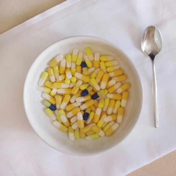 A bowl filled with medicine pills on a white tablecloth