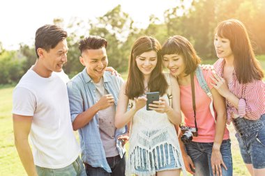 Asya insanlar bakmak bir şey cep telefonu parkta arkadaşlarıyla