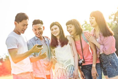 Asya insanlar bakmak bir şey cep telefonu parkta arkadaşlarıyla