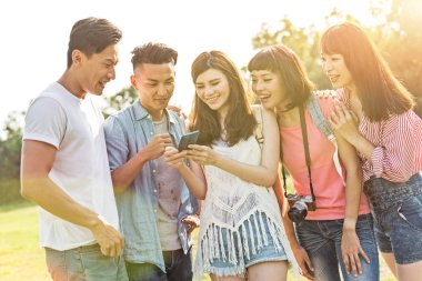Asya insanlar bakmak bir şey cep telefonu parkta arkadaşlarıyla