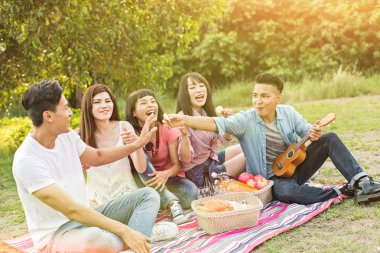 Asya genç adam parkta arkadaşlarıyla piknik al