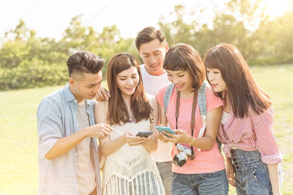 Asian people look something at cellphone with his friends in the park