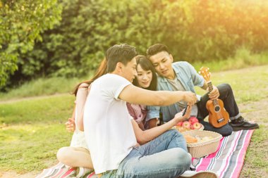 Asya insanlar bakmak bir şey cep telefonu parkta arkadaşlarıyla
