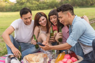 Asya insanlar bakmak bir şey cep telefonu parkta arkadaşlarıyla