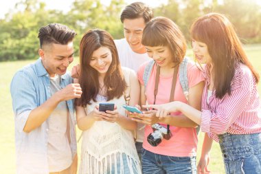 Asya insanlar bakmak bir şey cep telefonu parkta arkadaşlarıyla