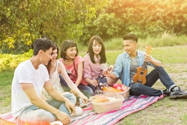 Asya genç adam parkta arkadaşlarıyla piknik al