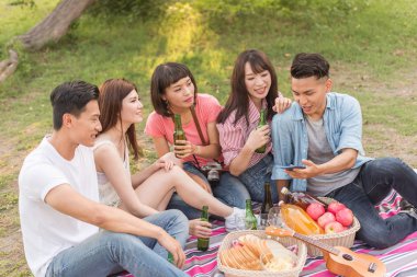 Asya insanlar bakmak bir şey cep telefonu parkta arkadaşlarıyla