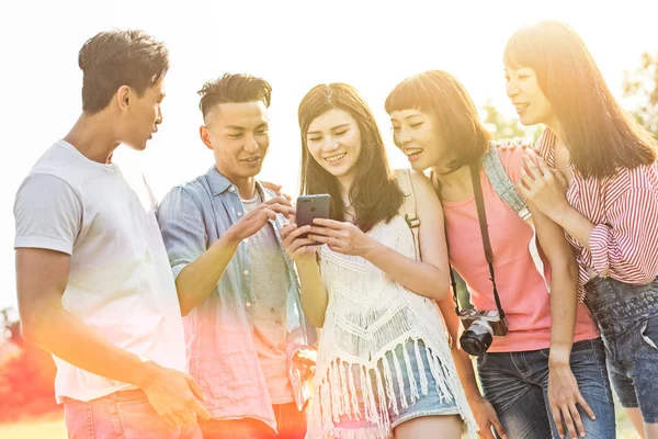 亚洲人在公园里和他的朋友们在手机上看东西 — 图库照片