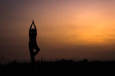 yoga ile genç kadın silüeti açık içinde poz