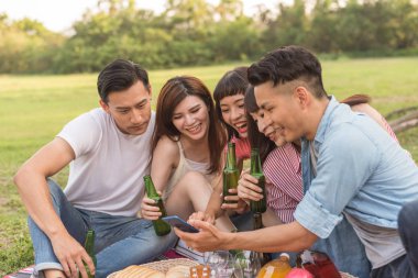 Asya insanlar bakmak bir şey cep telefonu parkta arkadaşlarıyla