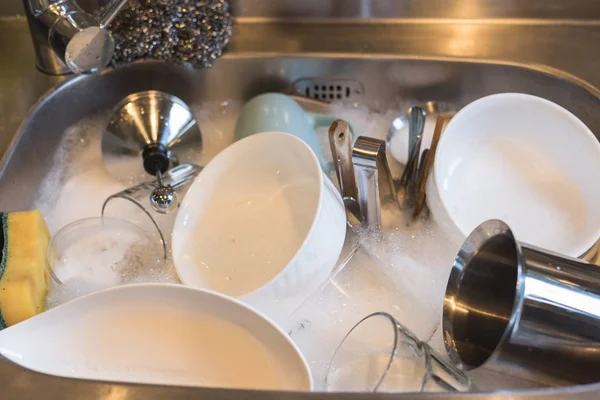 dirty dishes in the kitchen sink with water at home