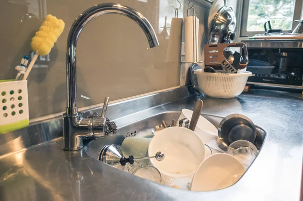 dirty dishes in the kitchen sink with water at home