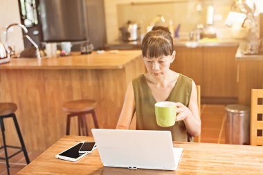 Asyalı olgun kadın dizüstü bilgisayar kullanıyor, evde çalışma kavramı