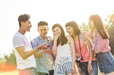 Asya insanlar bakmak bir şey cep telefonu parkta arkadaşlarıyla