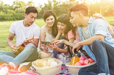 Asya insanlar bakmak bir şey cep telefonu parkta arkadaşlarıyla