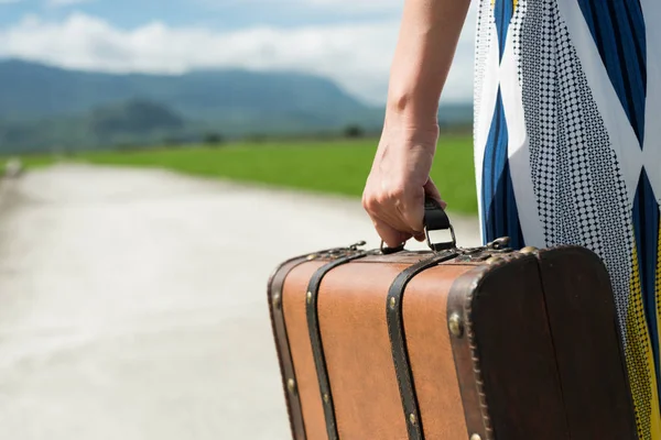 kırsal kesimde yolda bir bavul tutan kadın