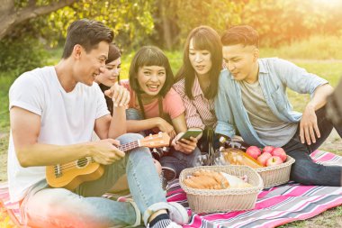 Asya insanlar bakmak bir şey cep telefonu parkta arkadaşlarıyla