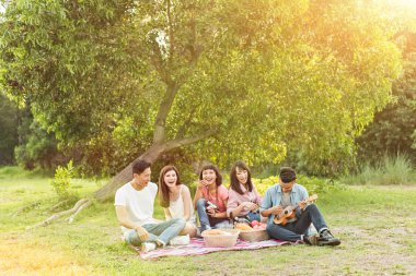 Asya genç adam parkta arkadaşlarıyla piknik al