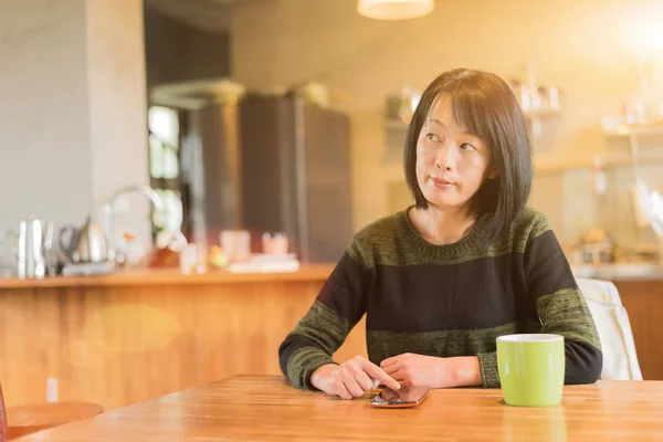 亚洲成熟妇女在家使用智能手机 — 图库照片