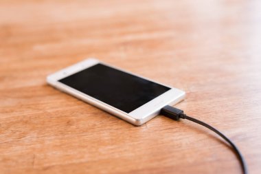 Ahşap masanın üzerinde şarj mobil akıllı telefon